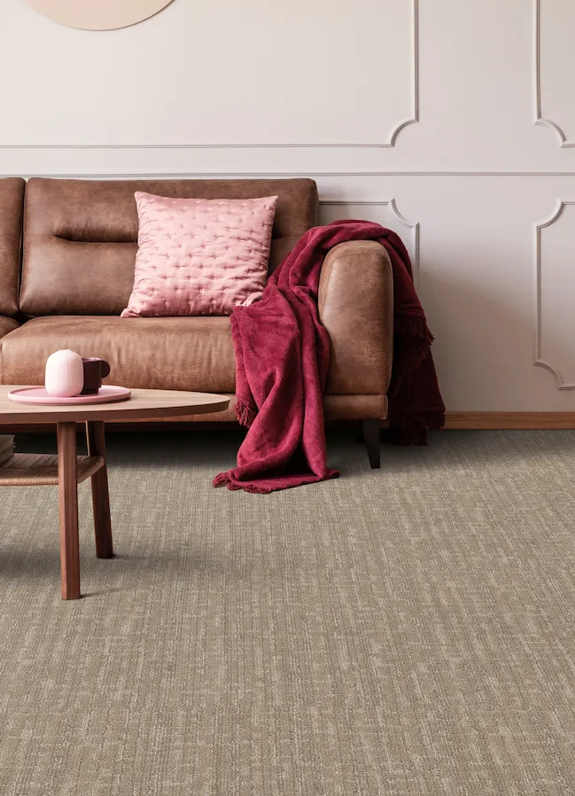 brown carpets in a cozy living room with a brown leather couch and pink accents